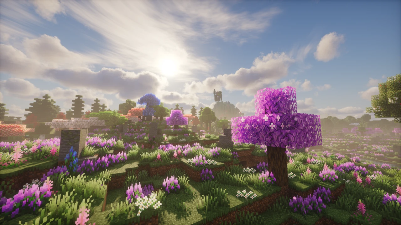 A flower meadow with a large pink blossom tree in the foreground and blue and pink trees behind it
